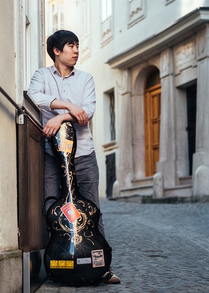 Fu Ping Ryu avec son étui à guitare dans une ruelle viennoise
